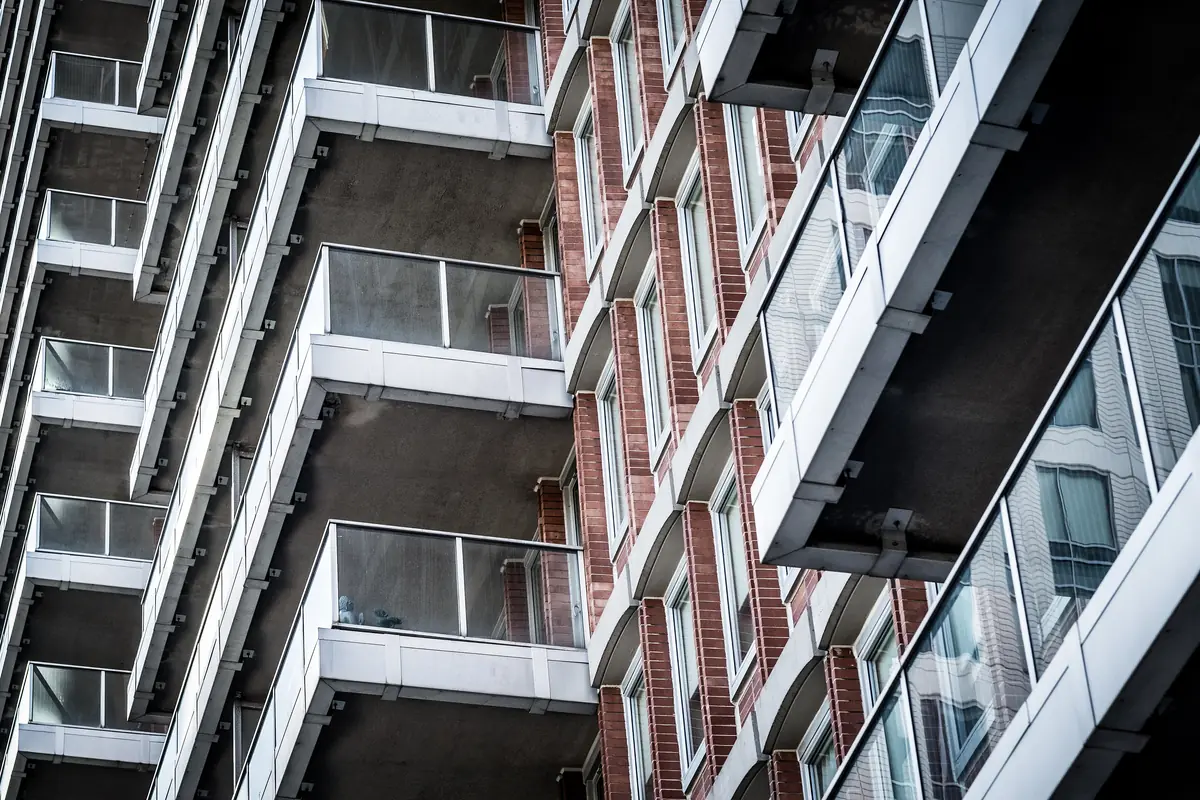 Stacked condo balconies with frosted and clear glass railing panels rising up a residential tower