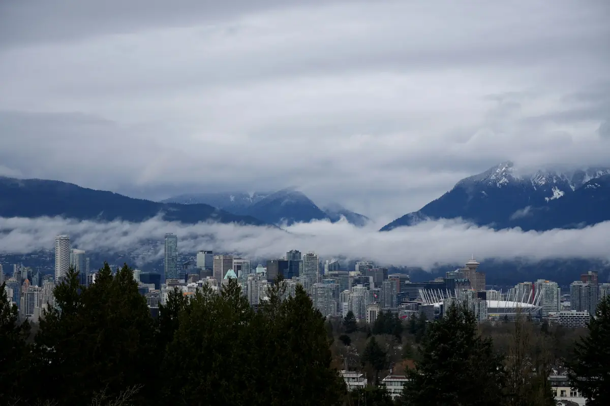 Grey rain cloud lying across the North Shore mountains behind downtown Vancouver towers