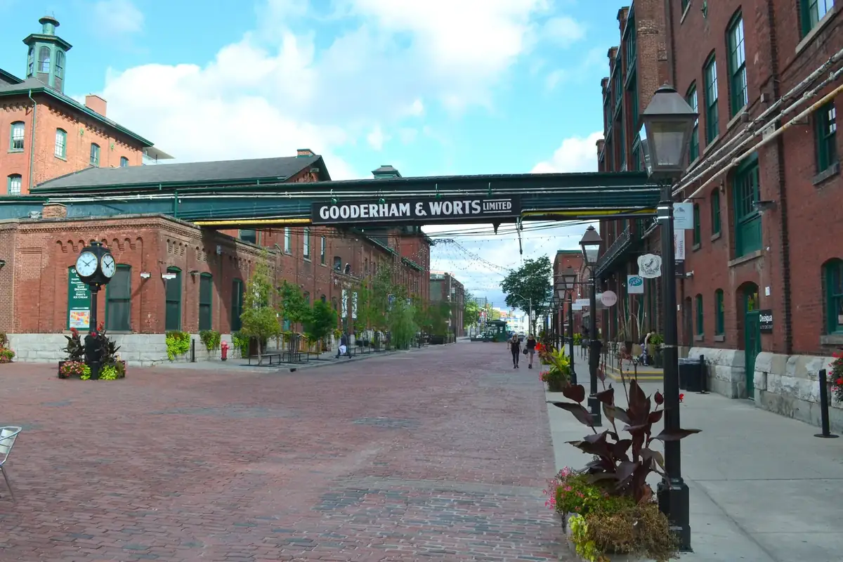 The brick-paved main street of the Distillery District, with the Gooderham & Worts sign bridge and brick warehouses, Toronto