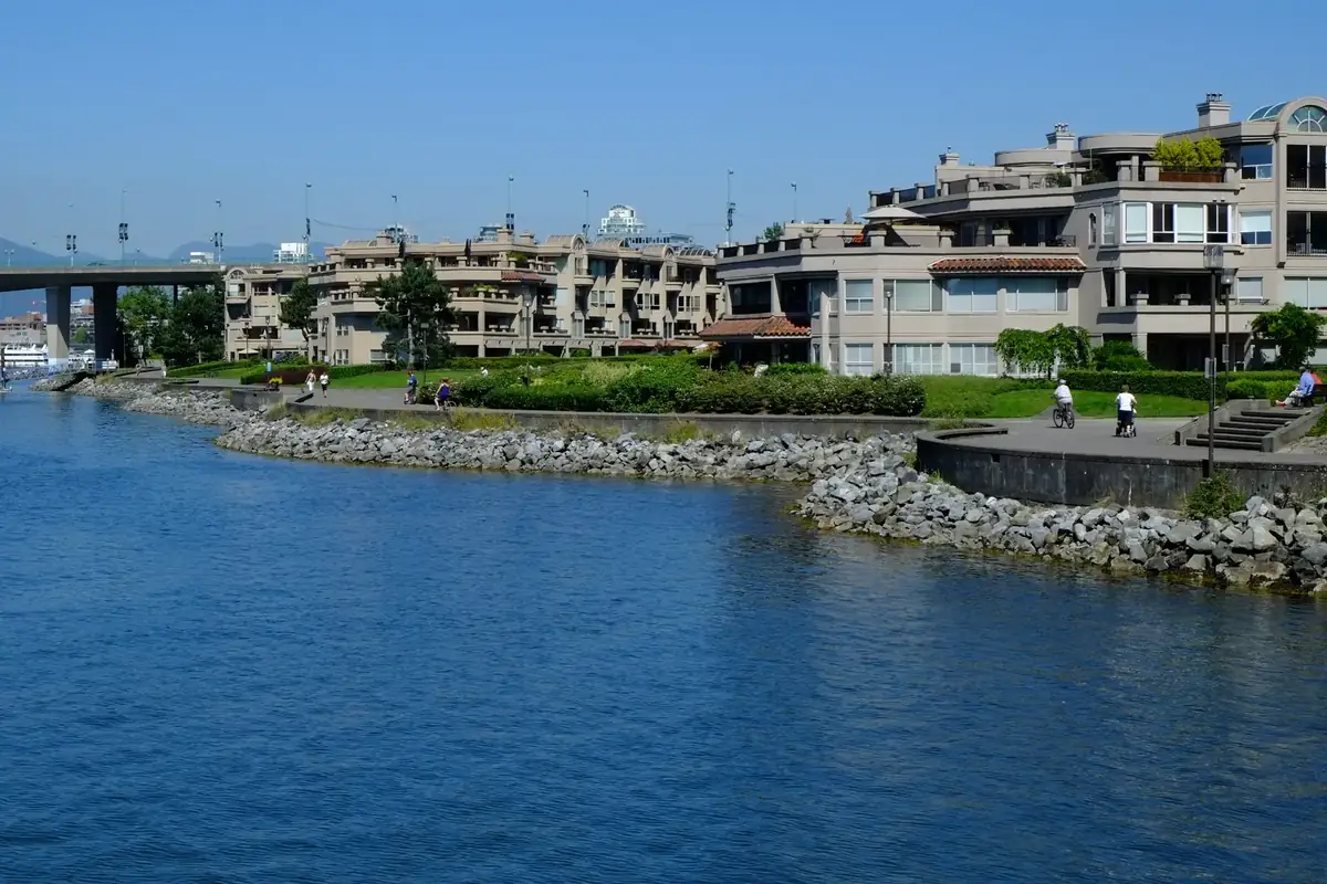 Terraced waterfront homes and gardens along the False Creek seawall in Fairview, Vancouver, with the Cambie Bridge beyond