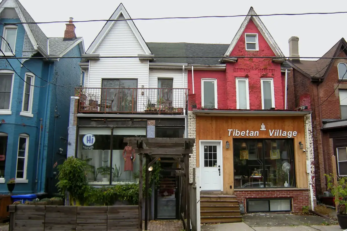 Painted Victorian houses in blue, white and red with small shops at street level in Kensington Market, Toronto