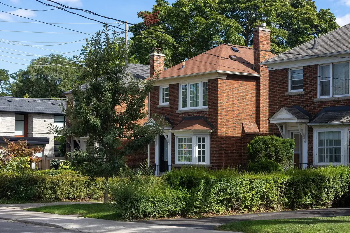 Red-brick family homes behind neat hedges on Rumsey Road in Leaside, Toronto