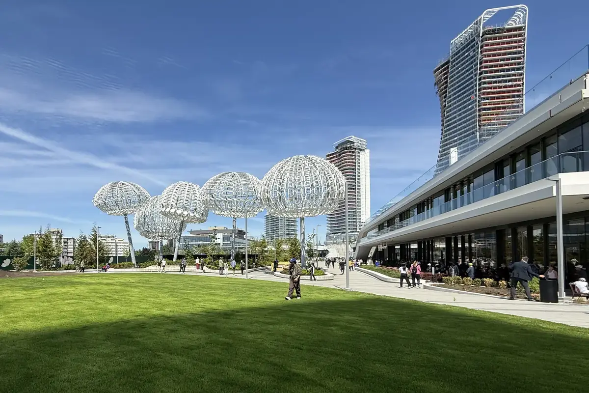 Rooftop park lawn at Oakridge Park, with white dandelion-like sculptures and the new towers under a blue sky, Oakridge, Vancouver