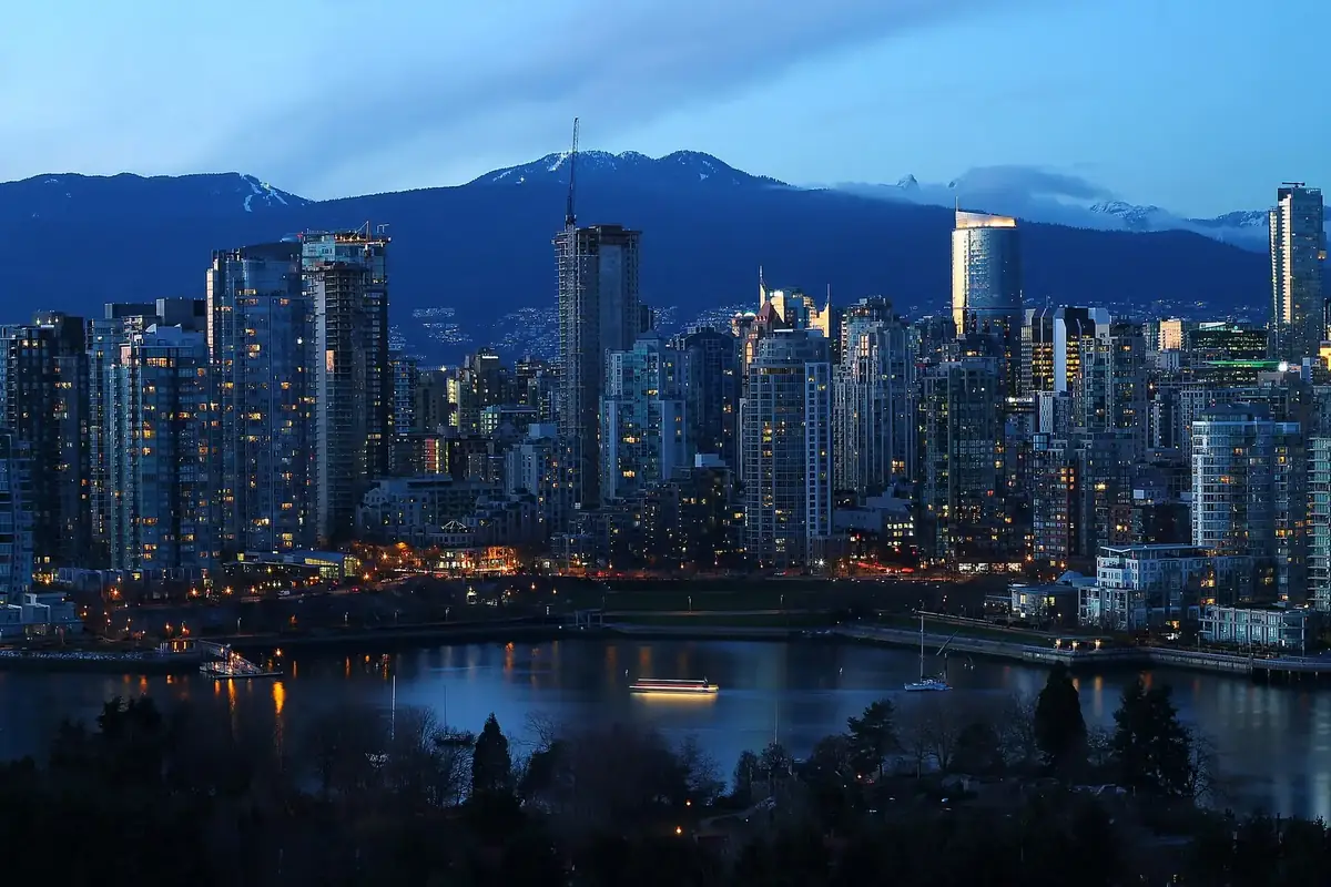 Yaletown towers glowing at dusk over False Creek, with the North Shore Mountains behind