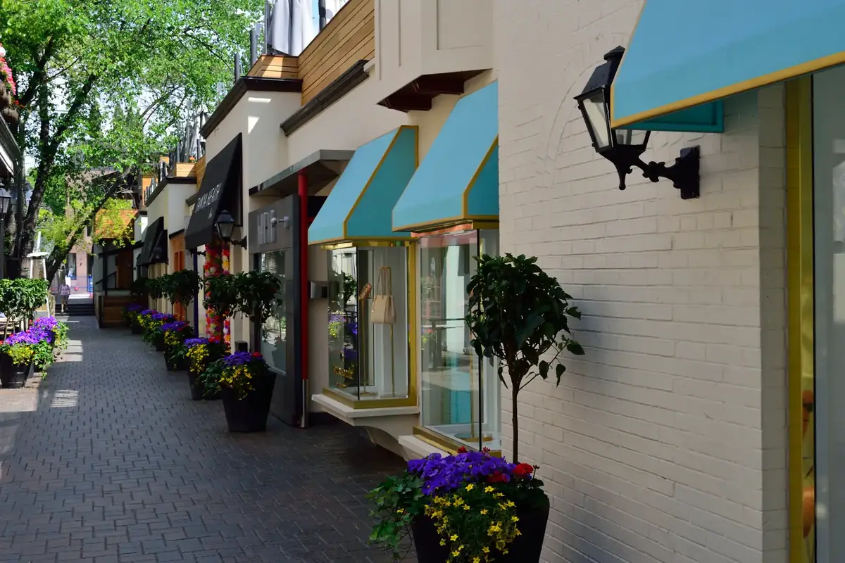 Boutique shopfronts with teal awnings and flower planters along Old York Lane in Yorkville, Toronto