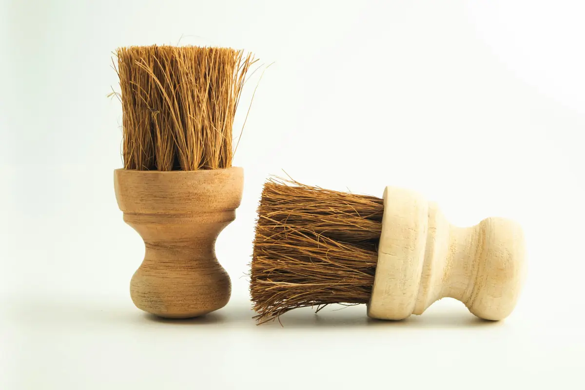 Two natural-fibre wooden scrub brushes on a white background