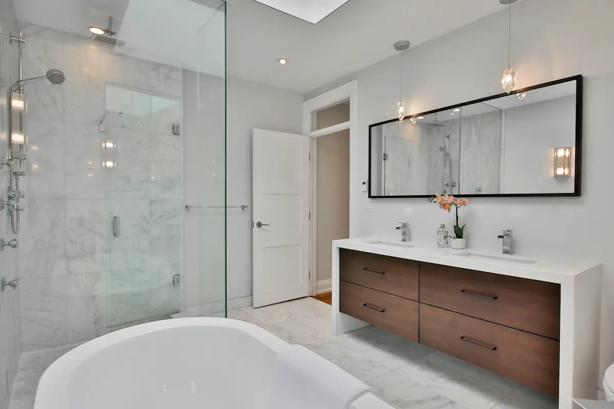 Bright marble ensuite with a freestanding tub, a glass shower and a walnut double vanity