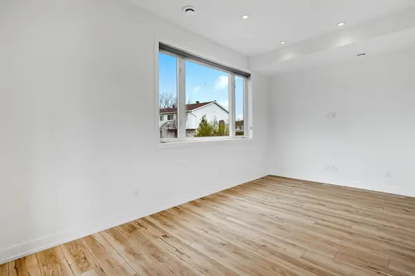 Empty, freshly finished room with white walls and a light hardwood floor