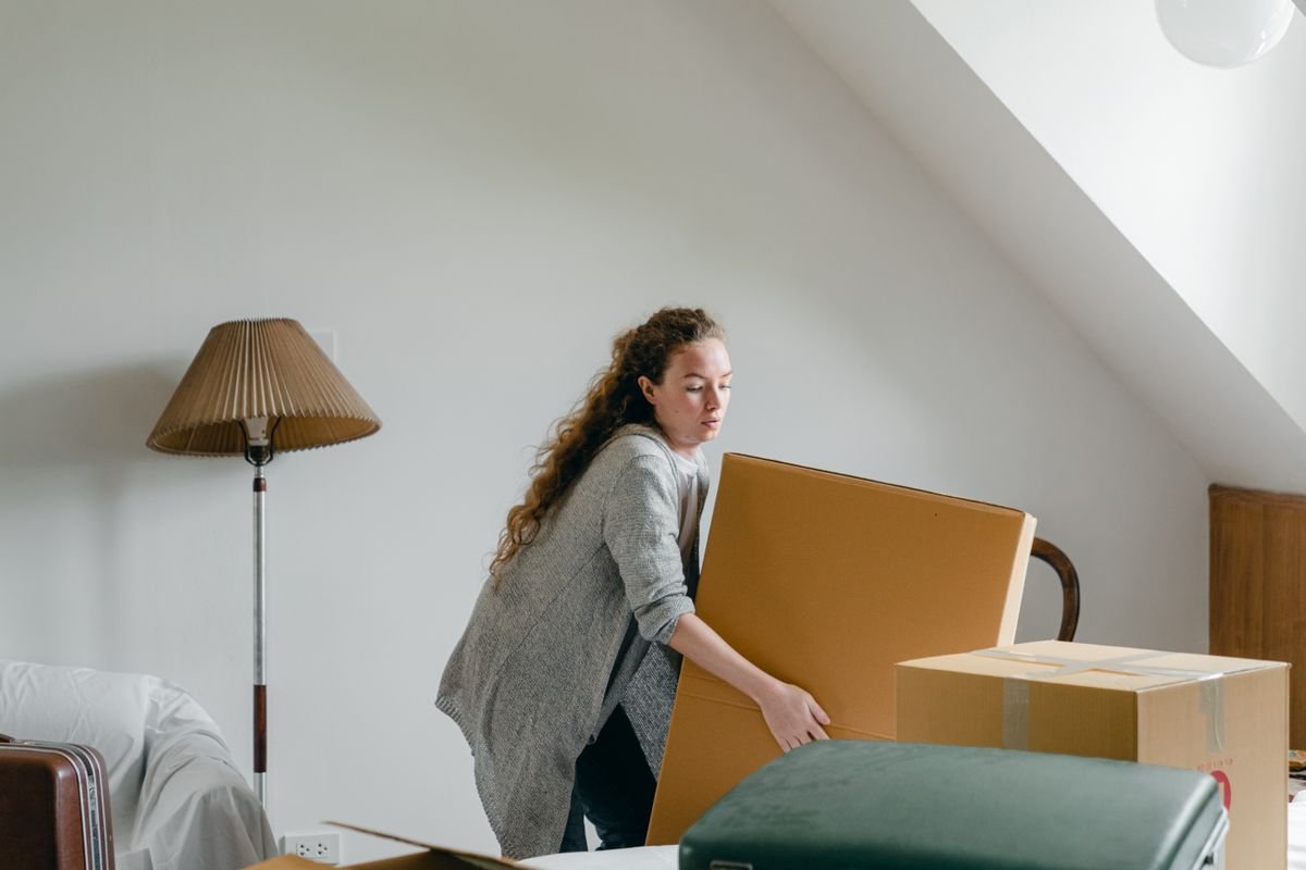 Woman carrying a large cardboard box while moving in