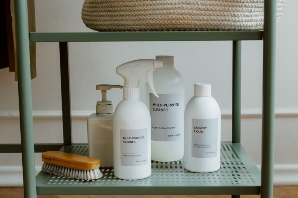 Cleaning supplies on a shelf: multi-purpose cleaner, laundry liquid and a scrub brush