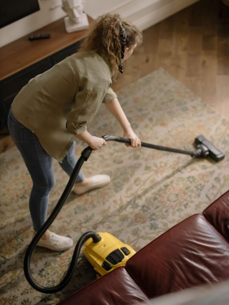 Woman vacuuming a patterned rug in a bright living room