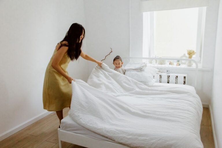 Professional housekeeper making a bed with fresh white linens in a bright bedroom