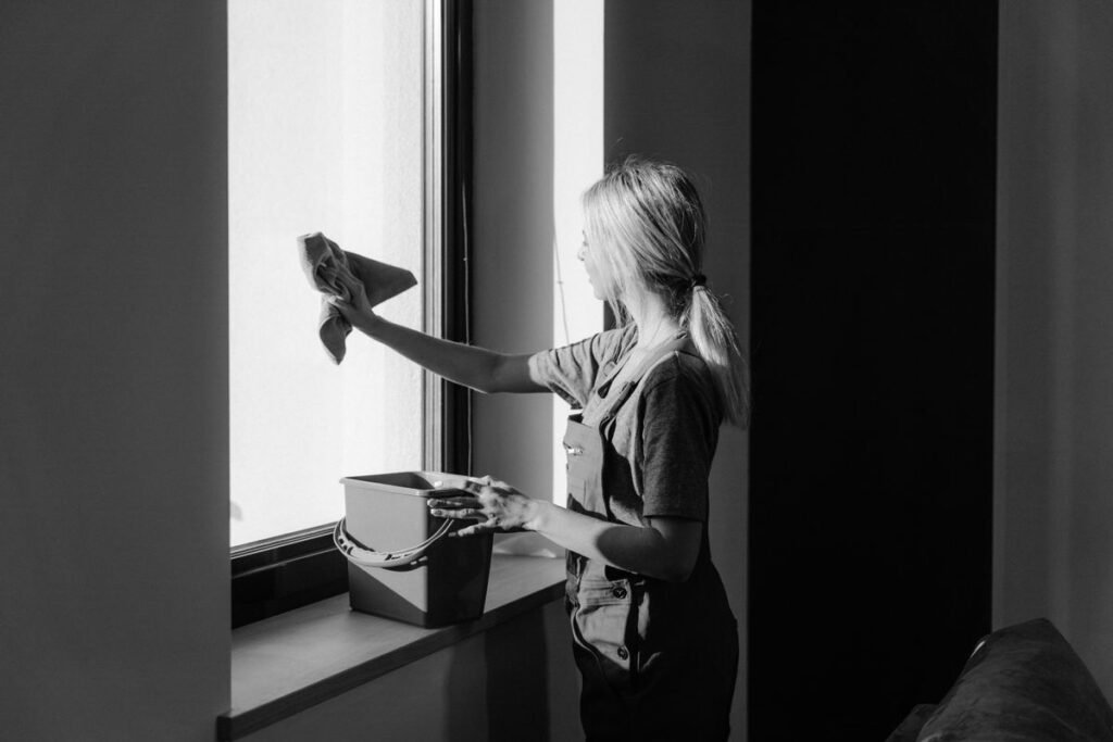 Person wiping a window clean with a cloth and bucket