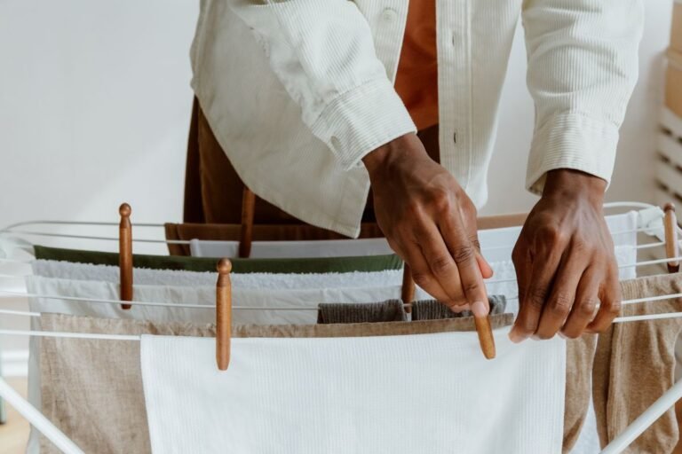 Clean white laundry air drying on a wooden rack in a bright home