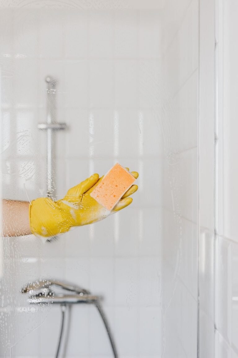 Wiping a glass shower screen and white subway tiles clean