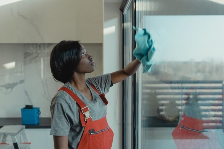 Professional cleaner wiping a large window pane with a blue microfiber cloth